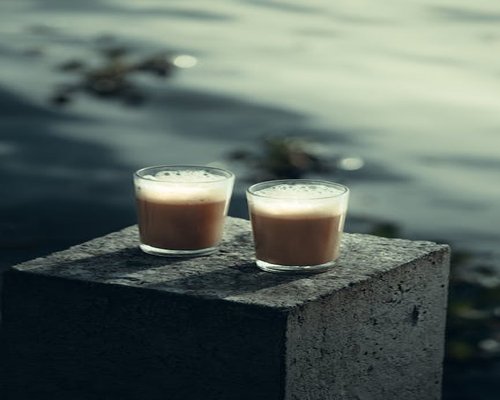A glass of water next to a cup of Indian Chai